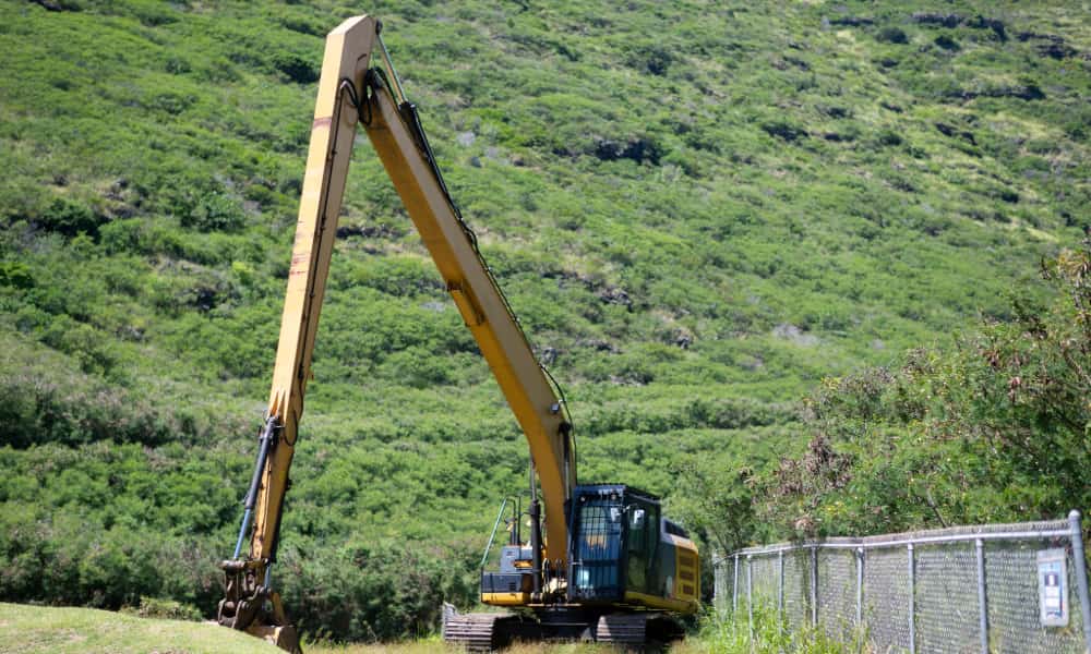An excavator working on a green hillside