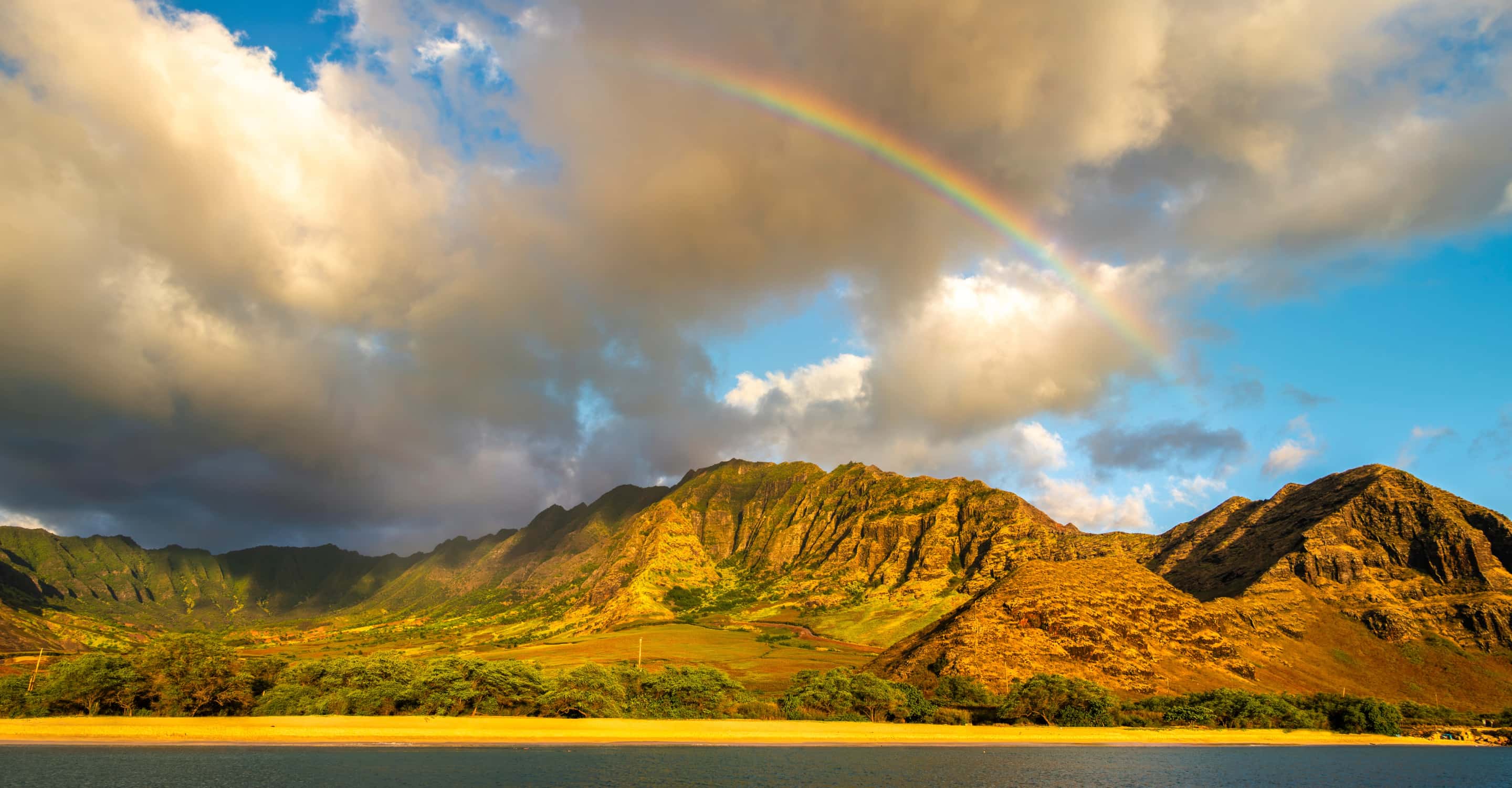 A rainbow arcing over the Waiʻanae range above a west Oʻahu shoreline